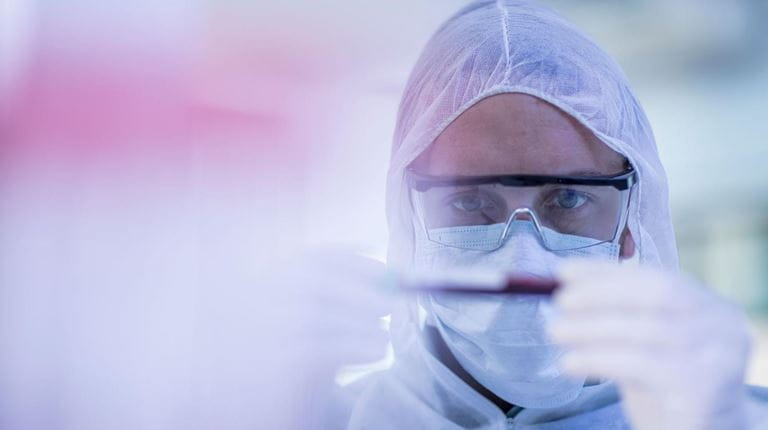 Wetenschapper die reageerbuis bekijkt